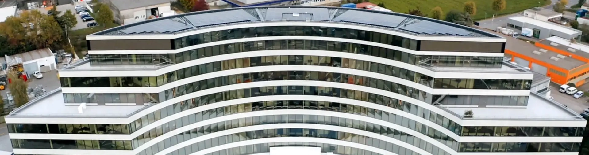 Corporate office building exterior with SpinetiX digital signage displaying company KPI dashboards, news feeds, and employee communications