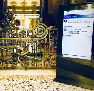 Freestanding digital signage totem at the entrance of Palazzo Castiglioni displaying visitor welcome messages, event schedules, and building directory
