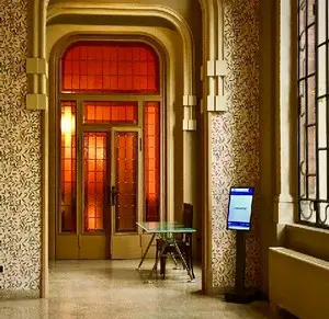 Digital event schedule displays at Palazzo Castiglioni showing conference room bookings, meeting times, and speaker information panels