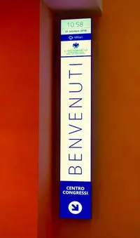 Ultra-wide stretched digital welcome screen at Palazzo Castiglioni entrance showing animated branding, event agenda, and personalized visitor greetings